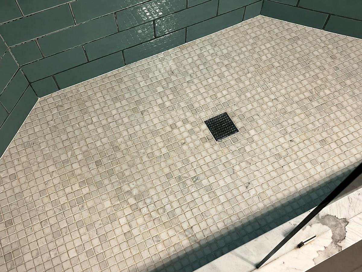 Clean tiled shower floor with green wall tile and square drain