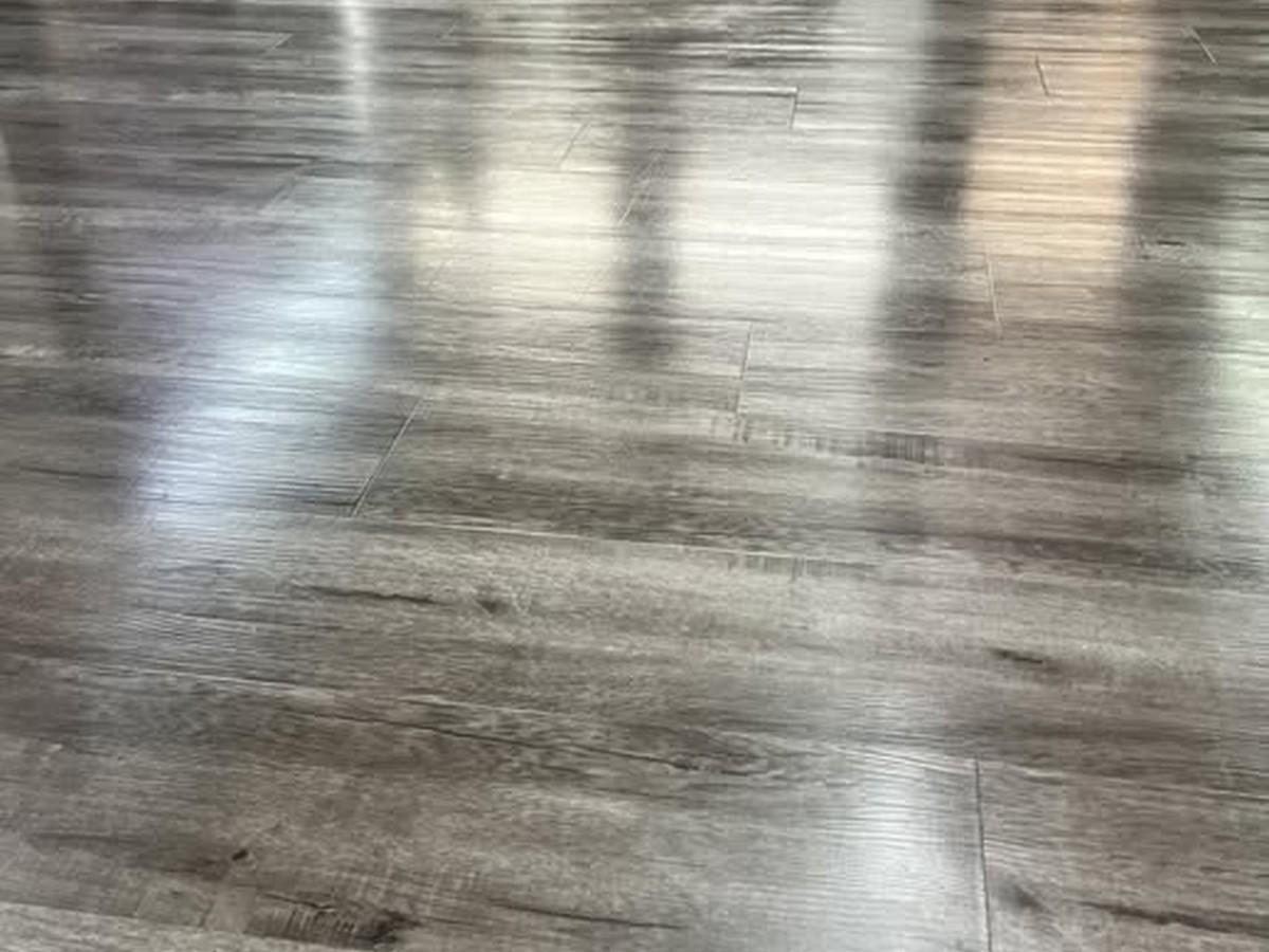 Polished gray vinyl plank flooring with a reflective shine