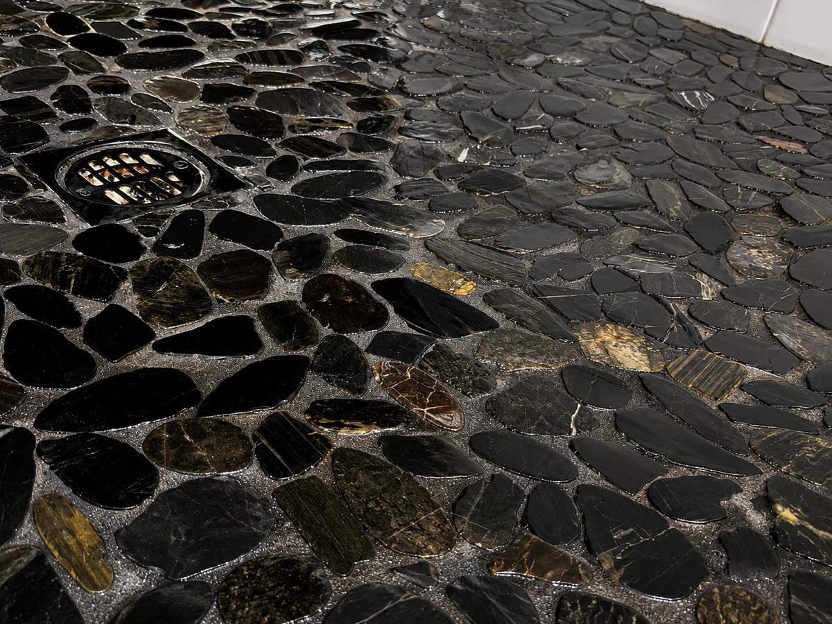 Dark pebble natural stone shower floor after restoration