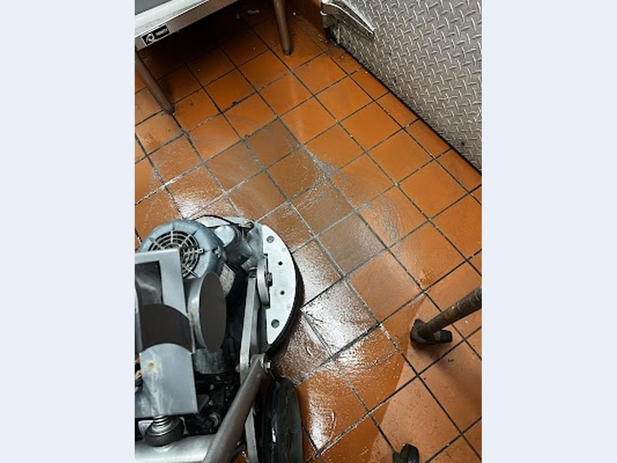 Professional machine deep cleaning an orange commercial kitchen tile floor